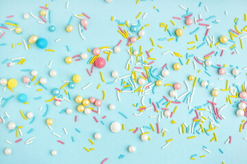 Sweet colorful sprinkles scattered on blue background