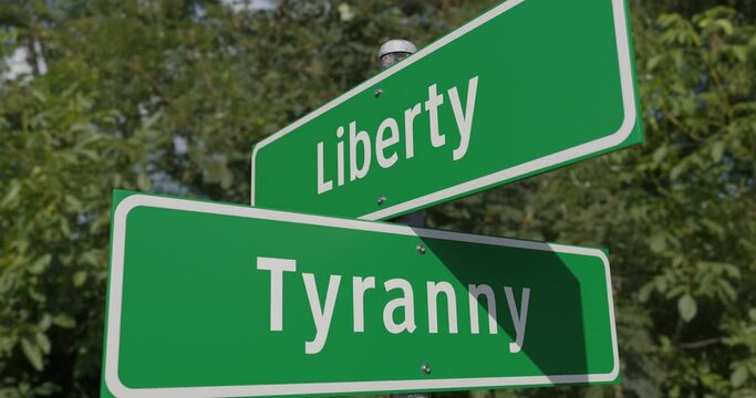 Pan of Liberty, Tyranny Two Way Green Road Sign Along The Road.
