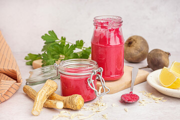 Horseradish sauce with beet in jars and horseradish root on white table