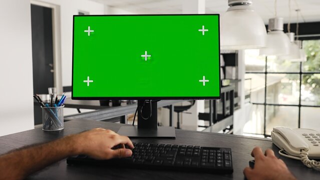 POV of businessman works at greenscreen pc in front of computer, solving daily tasks and looking at monitor running blank chromakey template at workstation. Worker uses mockup screen. Tripod shot.