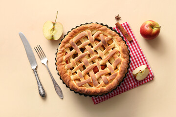 Tasty homemade apple pie with fruits, cinnamon and cutlery on beige background