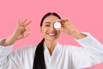 Beautiful young happy woman in bathrobe with dental floss showing OK gesture on pink background