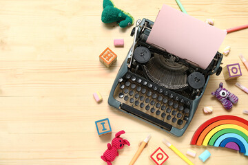 Composition with vintage typewriter, knitted toys and pink paper on light wooden background