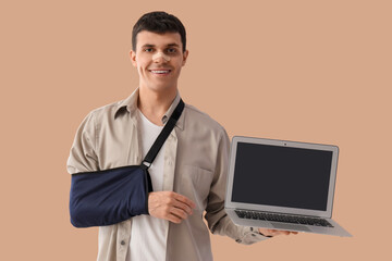 Injured young man after accident with laptop on beige background