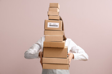 Woman holding many cardboard packages on pink background