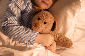 Adorable little girl with teddy bear sleeping in bed