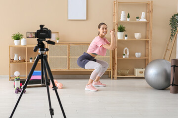 Sporty female blogger exercising and recording video at home
