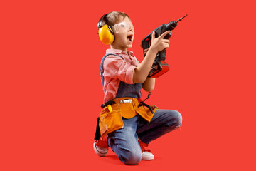 Cute little builder with drill on red background - obrazy, fototapety, plakaty