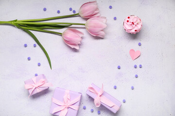 Frame made of presents, fresh tulips and cupcake on light background