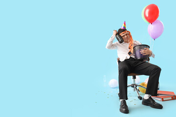 Young businessman with hangover and bin in chair after Birthday party on blue background