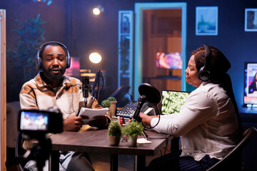 Content creators streaming live internet vlog using digital video camera from home studio. African american influencers recording podcast for posting on social media using professional audio equipment
