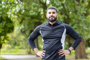 Confident man standing with hands on hips in a park