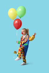 Cute little girl in clown costume with balloons on blue background