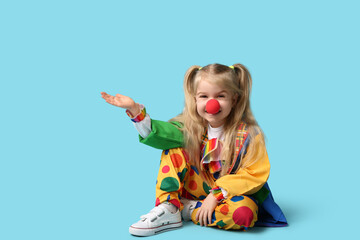 Smiling little girl in clown costume on blue background