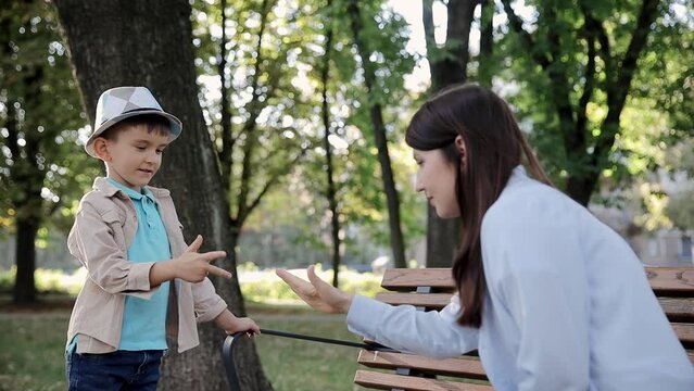 Portrait of a little boy on a modern playground playing the game rock paper scissors with his aunt. Mother and son playing game in the park