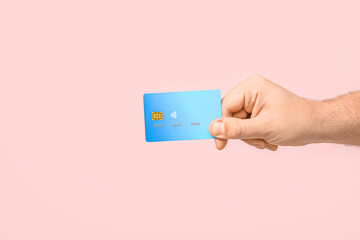 Male hand with credit card on pink background