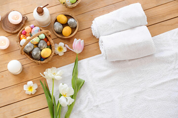 Fototapeta na wymiar Spa composition with Easter eggs, burning candles, tulips and towels on wooden table, top view