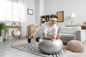 Sporty young man training on fitball at home