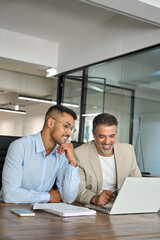 Two busy happy business men partners working together talking using laptop in office. Male manager and employee looking at computer discussing investment business project at office meeting. Vertical