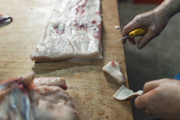 Close up of butchers hands slicing raw steak on butchers block. High quality photo