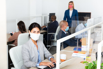Portrait of confident businesswoman in protective face mask working in open plan office. Concept of...