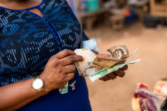 A woman counts naira notes as she pays for meat at Bodija Market in Oyo, Nigeria on Monday, February 19, 2024. 