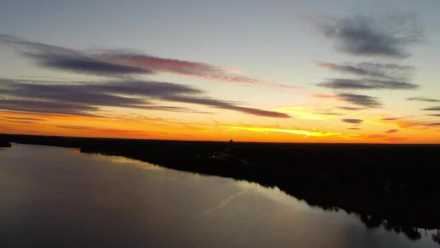 Aerial Idyllic Shot Of Rippled River And Trees, Drone Flying Backwards Over Trees Under Orange Clouds At Sunset - Buckner, California