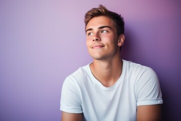 Portrait of a handsome young man looking up against purple background.