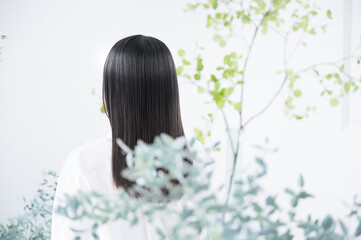 Obraz na płótnie Canvas To beauty hair care image of a young woman's hair fluttering with organic and natural image of green Faceless back view 