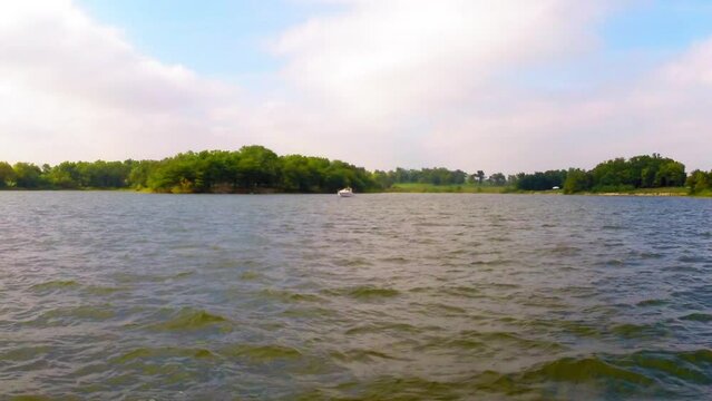 Aerial: Drone Forward Shot Of Nautical Vessel Moving On Waves In River By Green Trees Against Cloudy Sky - Buckner, California