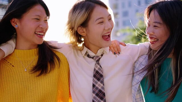 Cheerful Asian nice women friends walking carefree through city pointing to something in sky. Young happy Chinese female stroll embraced talking and laughing enjoying together spring sunny day outdoor