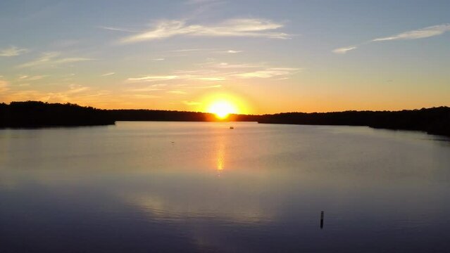 Aerial: Drone Forward Scenic View Of Rippled Lake Amidst Trees On Landscapes During Sunset - Buckner, California