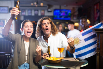 Fans with the flag of Uruguay celebrate the victory of their favorite team in a beer bar