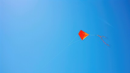 A solitary orange kite with tails flying against a vast, clear blue sky