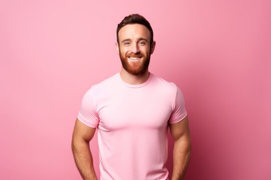 Portrait of a handsome young man in a pink t-shirt on a pink background.
