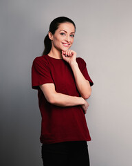Beautiful young happy casual woman in red t-shirt thinking and looking on blue studio background on empty copy space. Closeup - 764394380