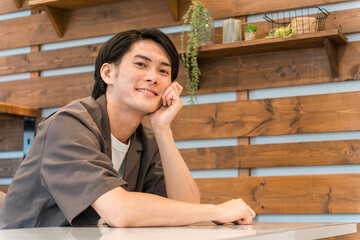 家・カフェでくつろぐ笑顔の若いアジア人・日本人男性（リラックス）
