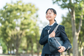 公園の中を通学する制服姿の中学生・高校生の女の子
