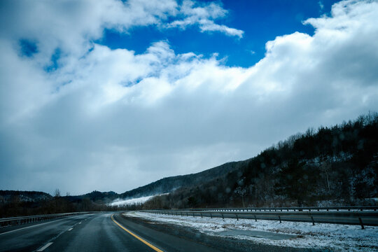 Winter road travel landscape with snow, clouds, and mountains on I-90 Interstate Highway in Upstate New York, USA