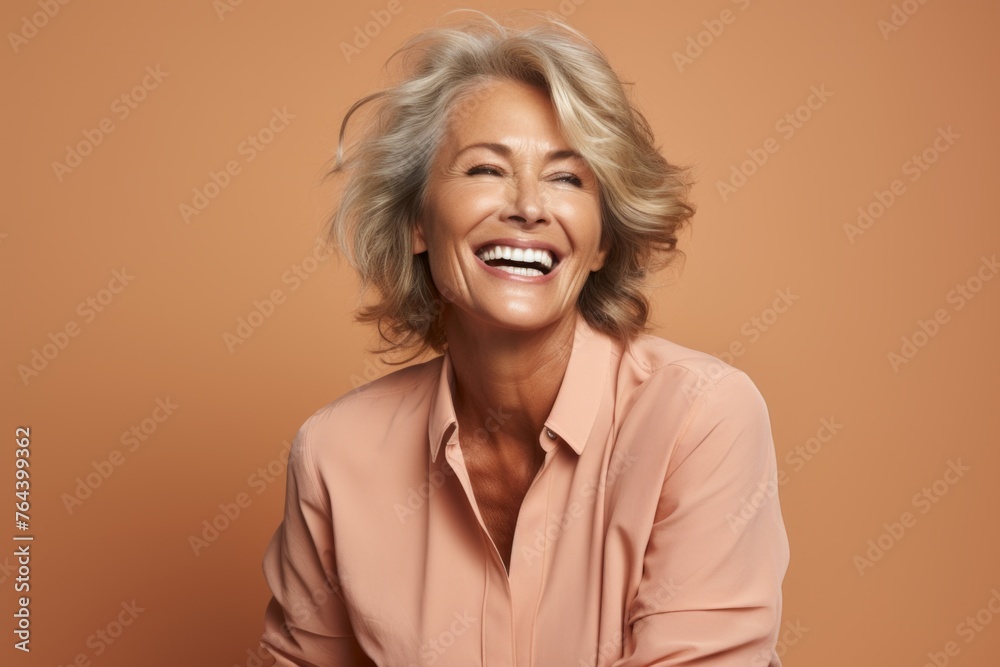 Wall mural mature woman laughing. portrait of happy senior woman laughing while standing against brown backgrou