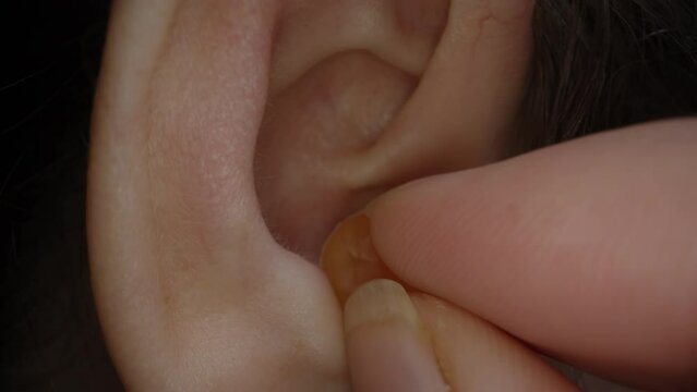 A Woman Inserts Silicone Earplugs. Protection Against Loud Sounds. Concept of Quiet Sleep.