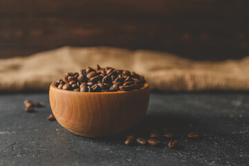 Fototapeta na wymiar Coffee beans in a wooden plate on a black background