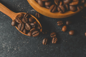 Coffee beans in a wooden plate on a black background