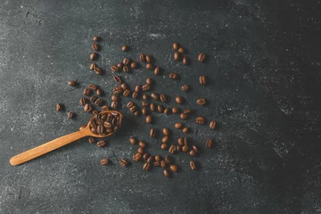 Rolgordijnen Coffee beans pour out from a wooden spoon on a retro background, top view © shine.graphics