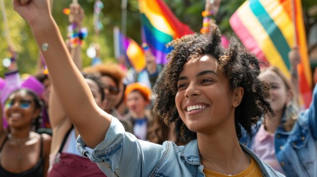 Joyful diverse crowd celebrating with vibrant flags at pride parade on sunny day. Unity in diversity and LGBTQ community support.