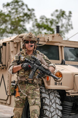 Confident soldier in full gear stands before a military vehicle, rifle in hand, showcasing readiness and strength.