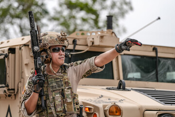 Confident soldier in full gear stands before a military vehicle, rifle in hand, showcasing...