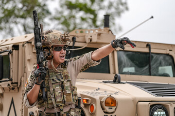 Confident soldier in full gear stands before a military vehicle, rifle in hand, showcasing...