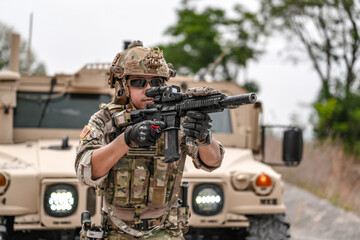 Confident soldier in full gear stands before a military vehicle, rifle in hand, showcasing...