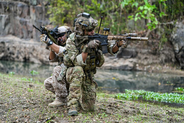 Soldiers in tactical gear aiming guns during a military exercise, showcasing teamwork and defense...